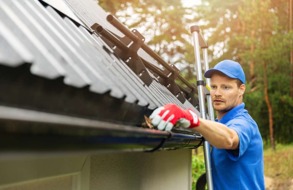 Man in blue providing gutter services for home owner